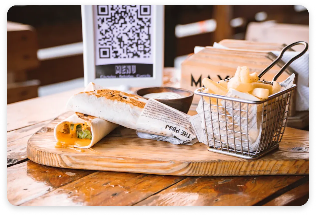 A mock showing a Voyce Feedback QR code printed on a menu sitting on a table in front of some food.